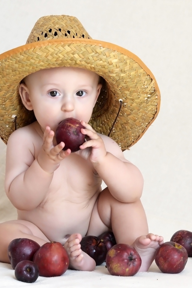 Малыш в шляпе грызет яблоки