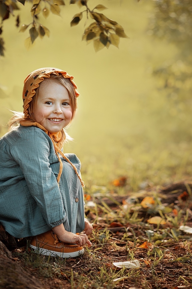 Красивая улыбающаяся девочка сидит под деревом