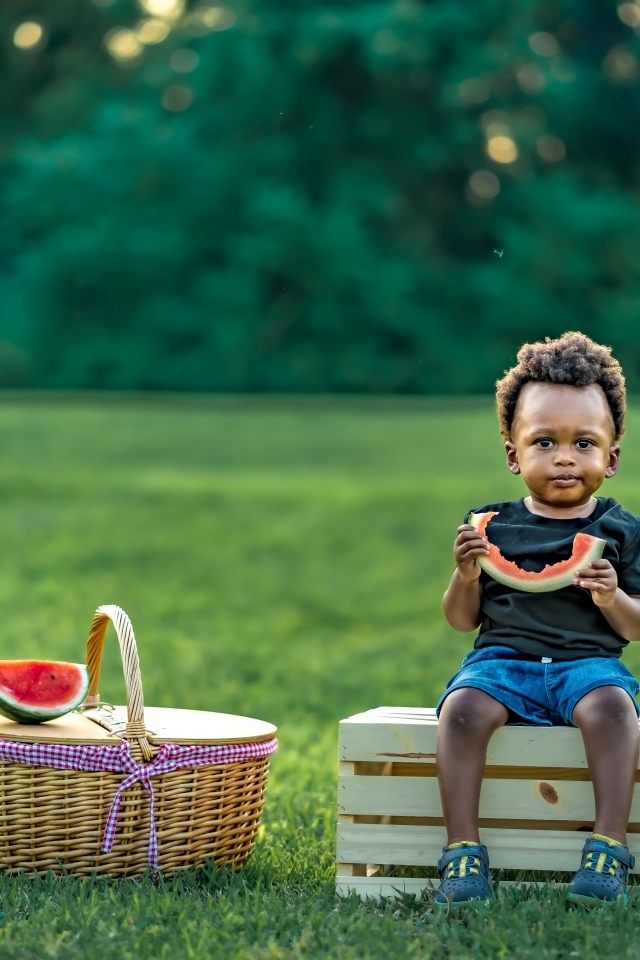 Темнокожий мальчик ест арбуз на природе