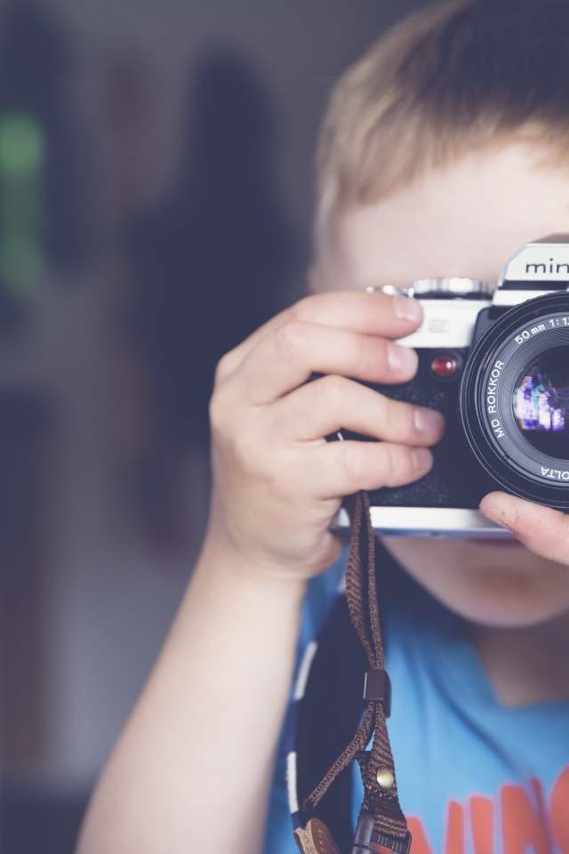 Мальчик держит в руках старый фотоаппарат