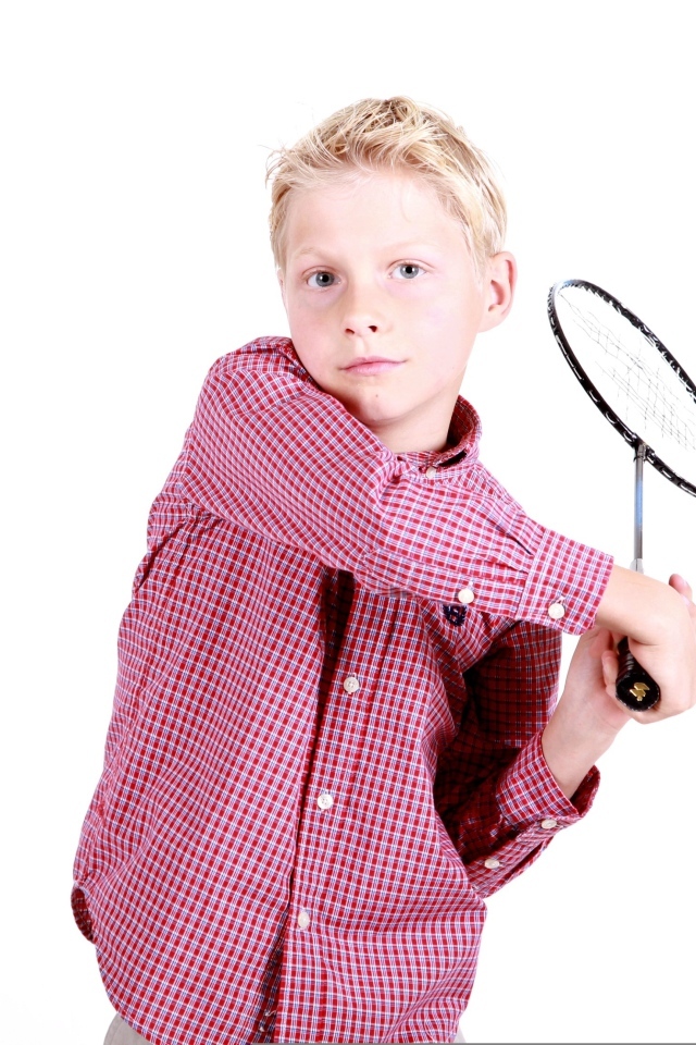 Мальчик в рубашке с ракеткой в руках на белом фоне