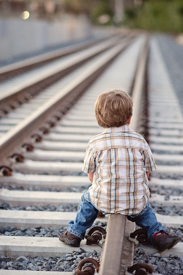 Мальчик сидит на железнодорожных рельсах