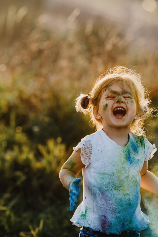 Веселая девочка в краске на улице
