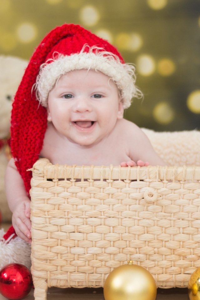 Ребенок в корзине в новогодней шапке с игрушками