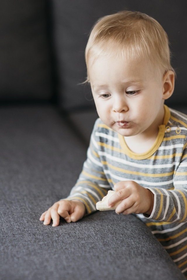 Любопытный маленький ребенок у дивана