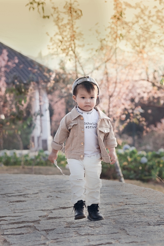 Милый мальчик гуляет по дороге у дома