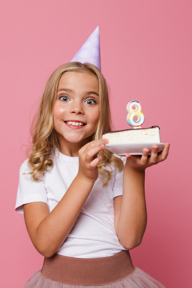 Милая девочка отмечает день рождения на розовом фоне