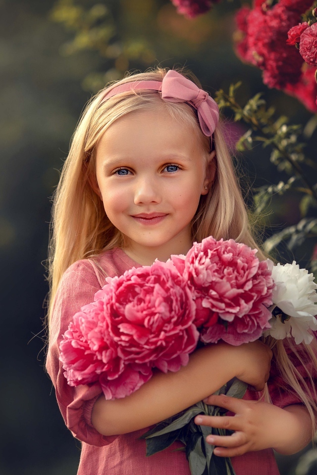 Милая маленькая девочка с букетом пионов