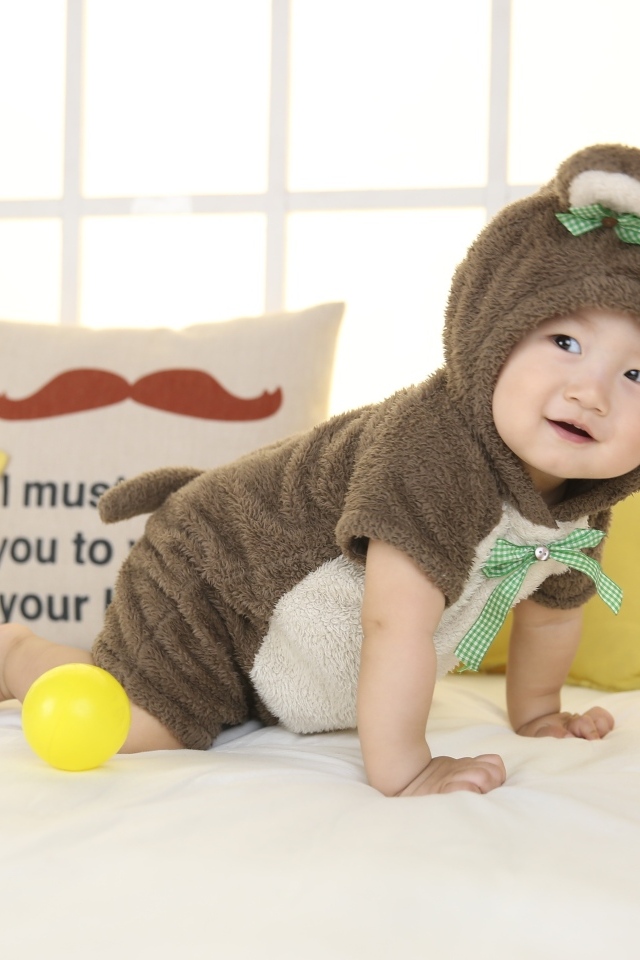 Смешной ребенок азиат в костюме на кровати