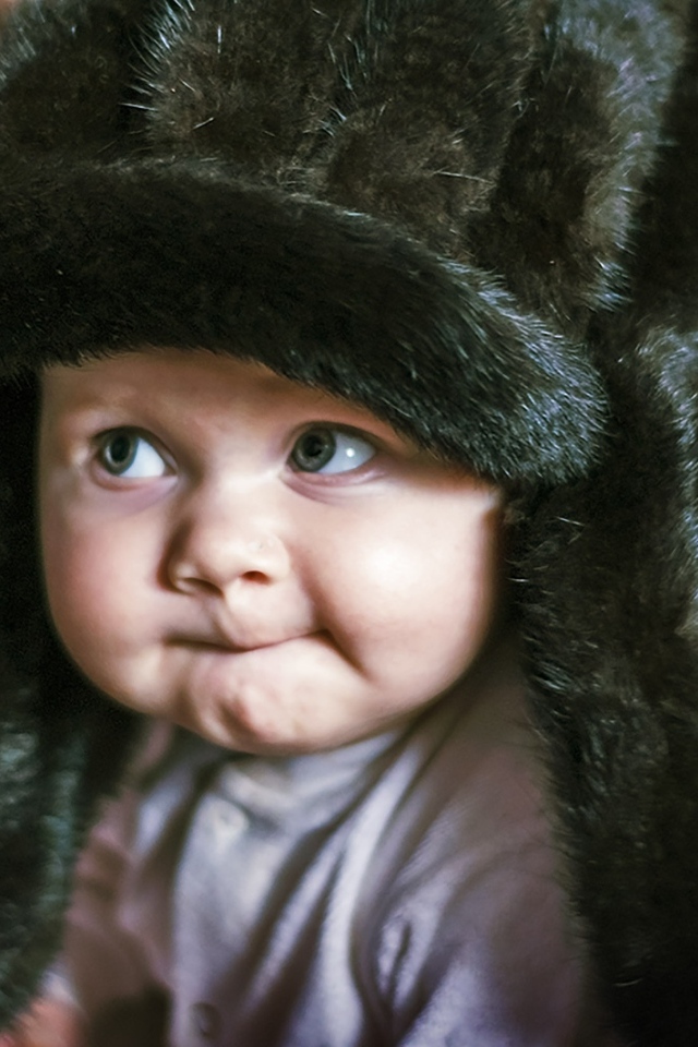 Смешной ребенок в черной меховой шапке