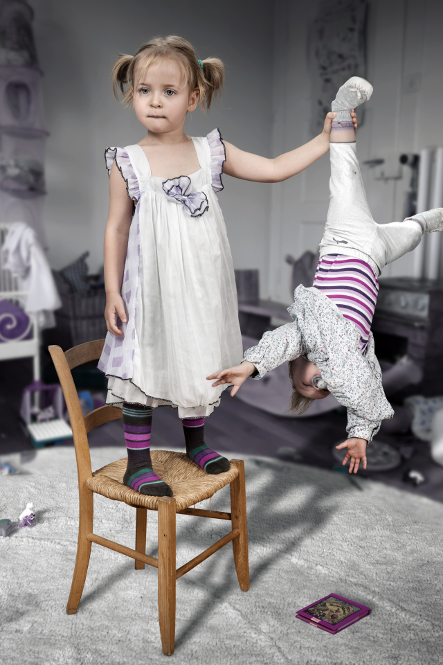 Девочка держит маленького брата за ногу