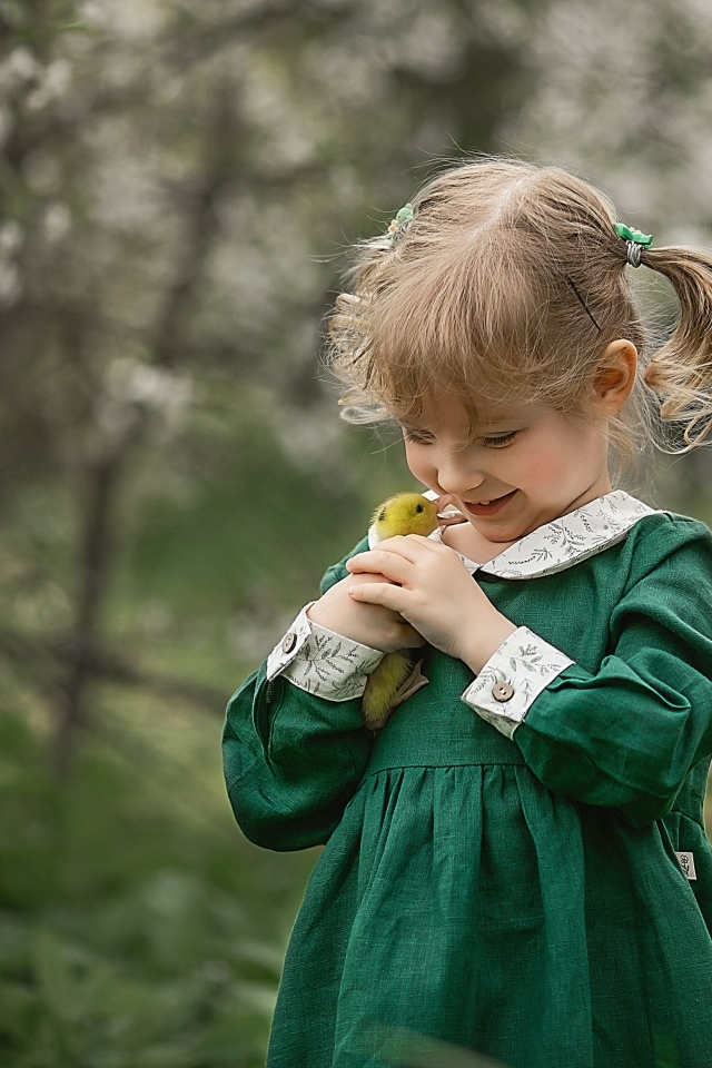 Девочка в зеленом платье с утенком в руках