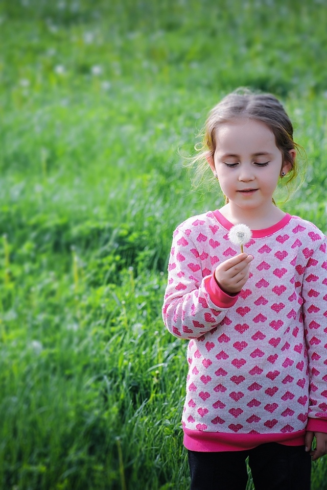 Девочка с одуванчиком на поле с зеленой травой