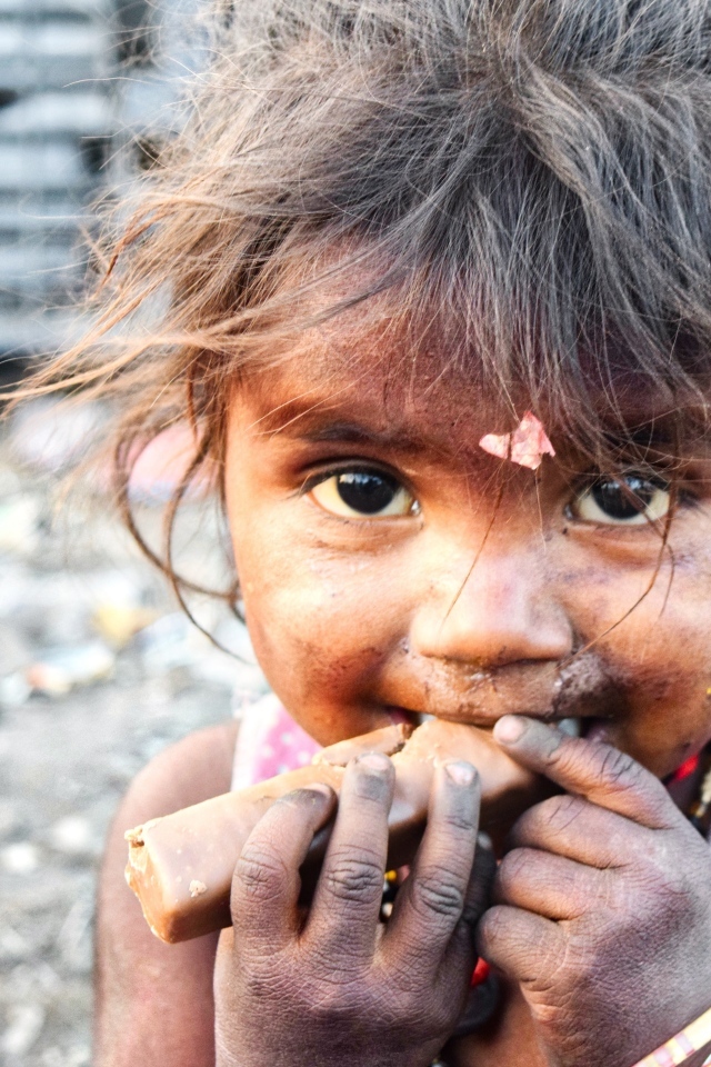 Маленькая азиатская девочка с конфетой в руках