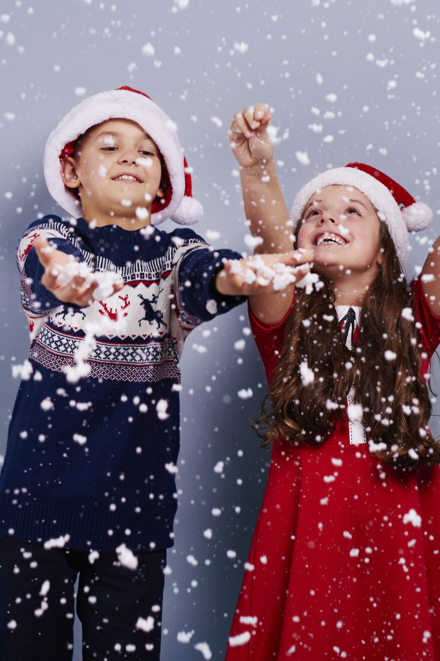 Маленькие мальчик и девочка ловят снег