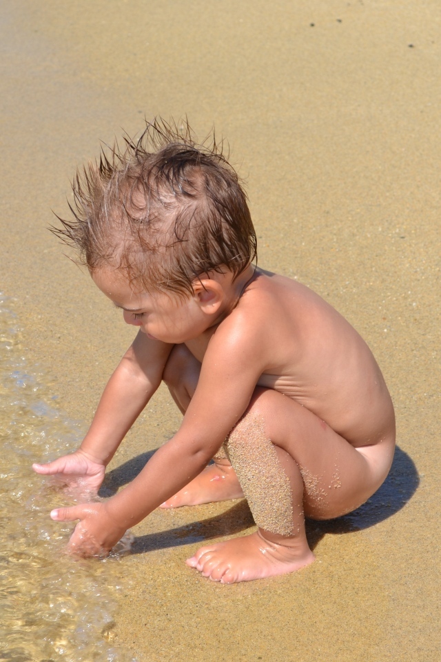 Маленький мальчик на пляже у моря на песке