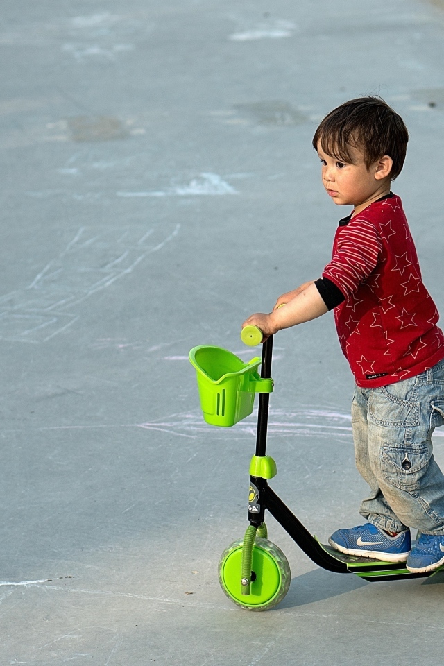 Маленький мальчик с зеленым самокатом