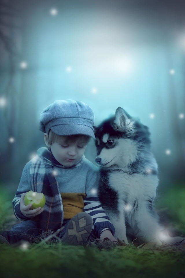 Маленький мальчик с щенком сидят на траве в лесу