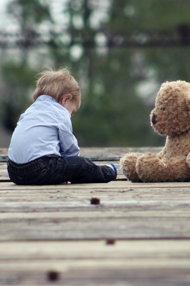 Маленький мальчик с игрушечным медведем на мосту