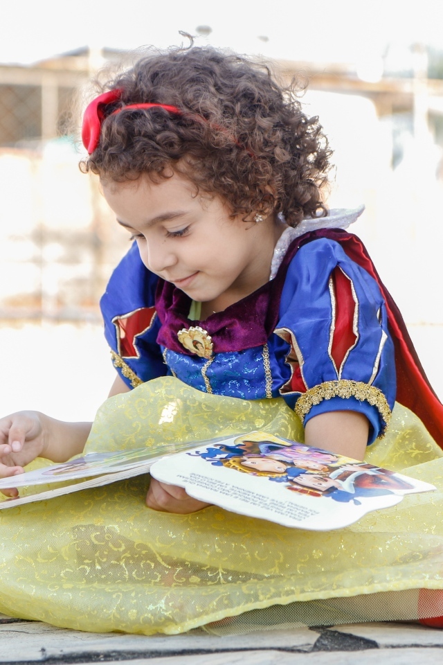 Маленькая девочка в костюме Белоснежки с книгой