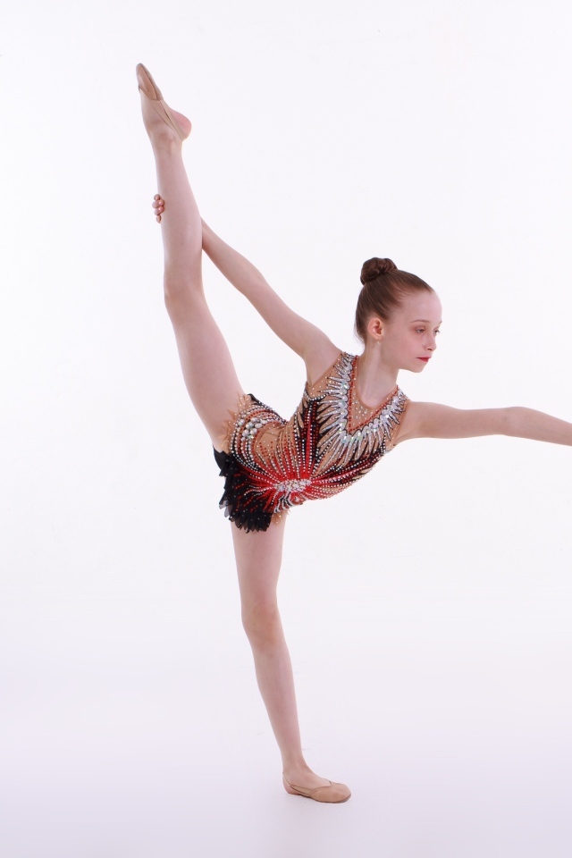 Маленькая девочка гимнастка на белом фоне