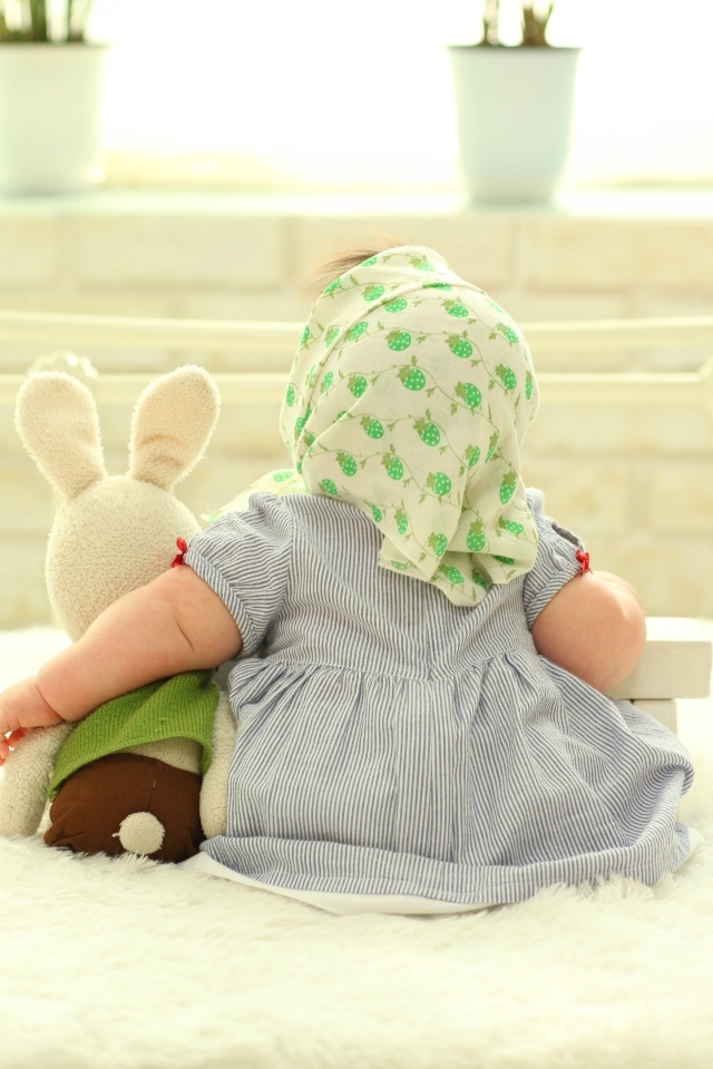 Маленькая девочка обнимает игрушечного зайца