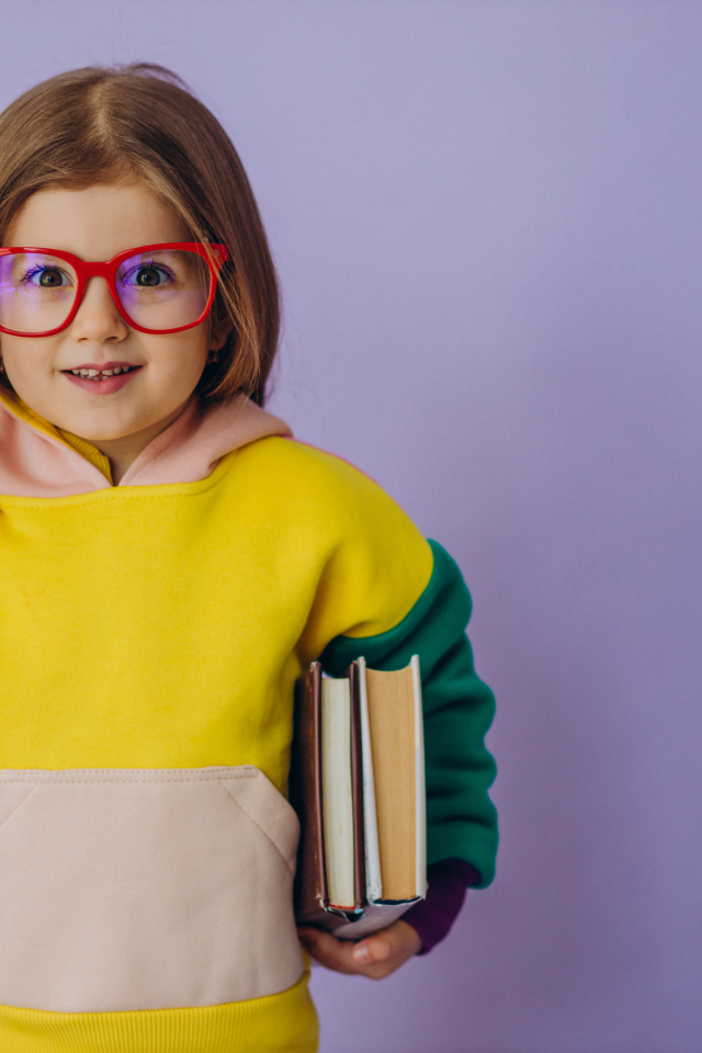 Маленькая девочка в очках с книгами в руке