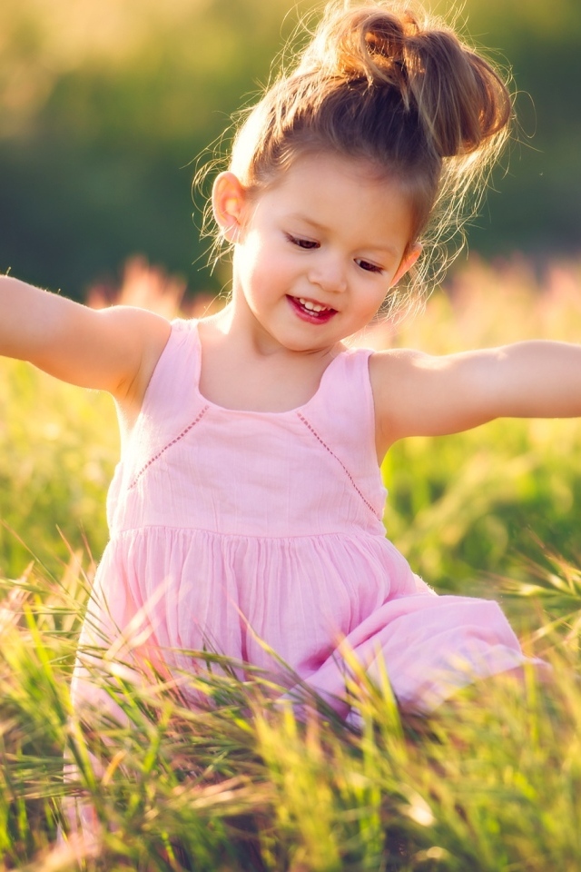 Маленькая девочка в розовом платье в зеленой траве