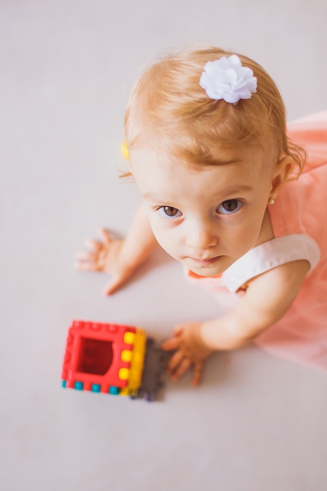 Маленькая девочка играет на полу с конструктором