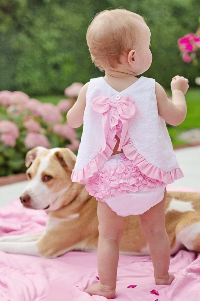 Маленькая девочка с собакой на розовом покрывале