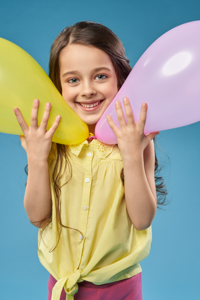 Маленькая девочка с воздушными шариками на голубом фоне