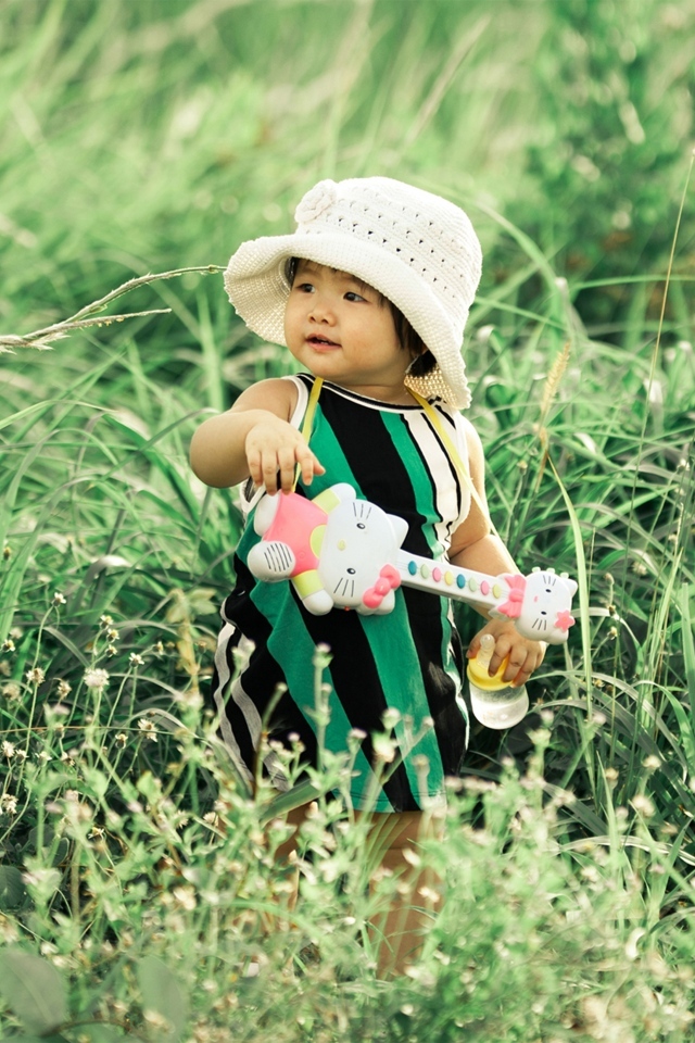 Маленькая девочка с игрушечной гитарой в траве