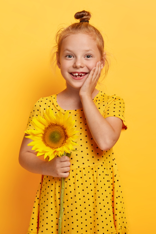 Маленькая рыжеволосая девочка с подсолнухом в руках