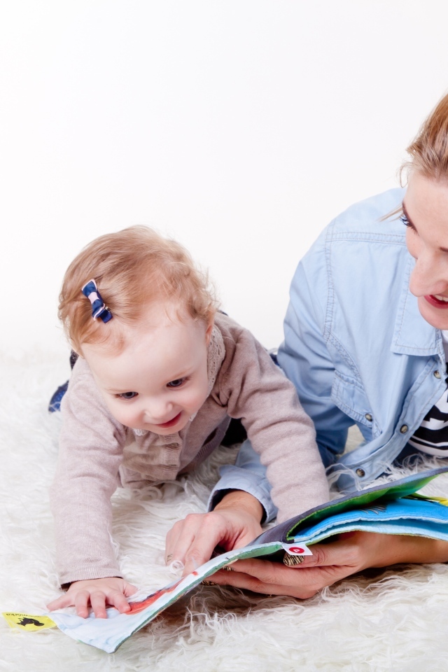 Мама читает книгу с девочкой 