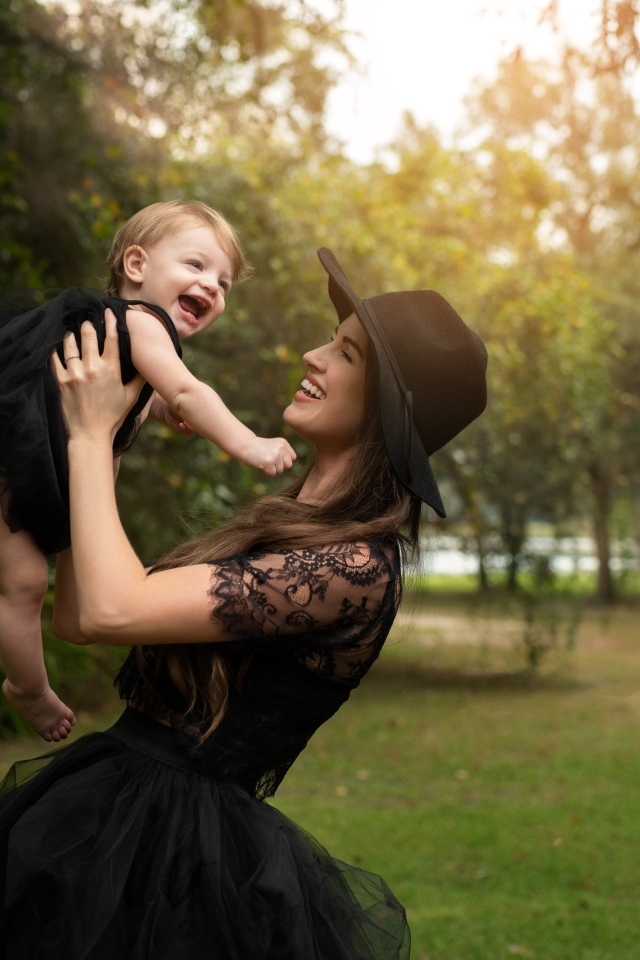 Мама держит улыбающуюся дочь на руках