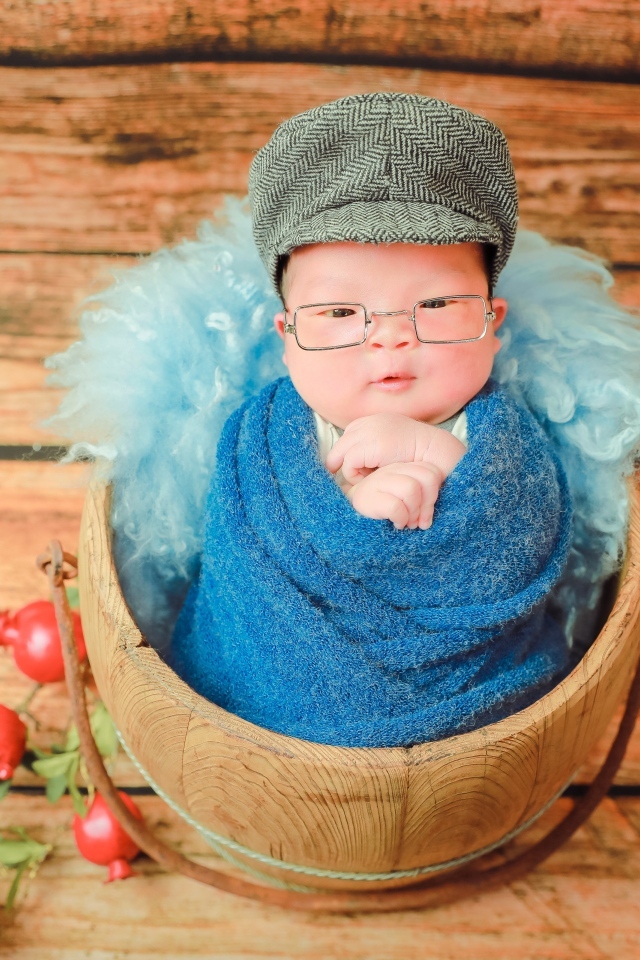 Новорожденный малыш в покрывале с кепкой на голове