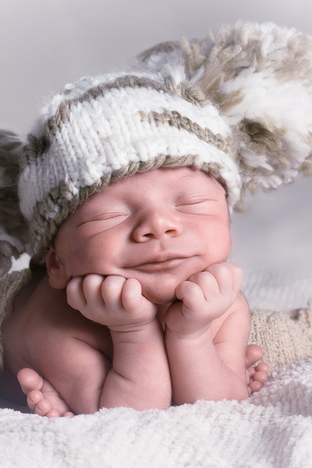 Новорожденный младенец в большой вязаной шапке