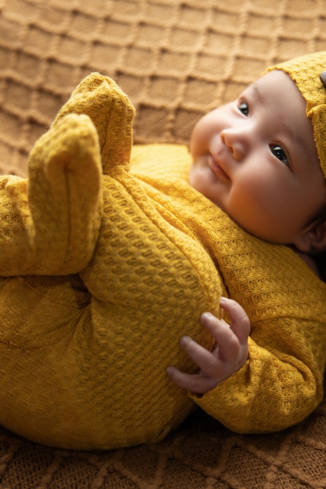 Новорожденный ребенок в желтом вязаном костюме и шапке