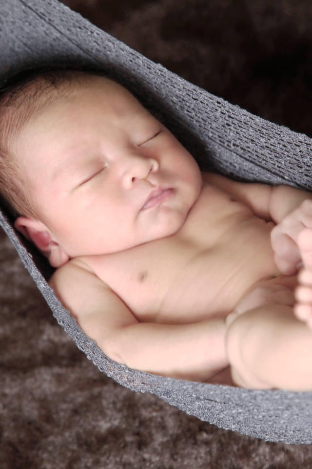 Новорожденный спящий малыш в вязаном гамаке