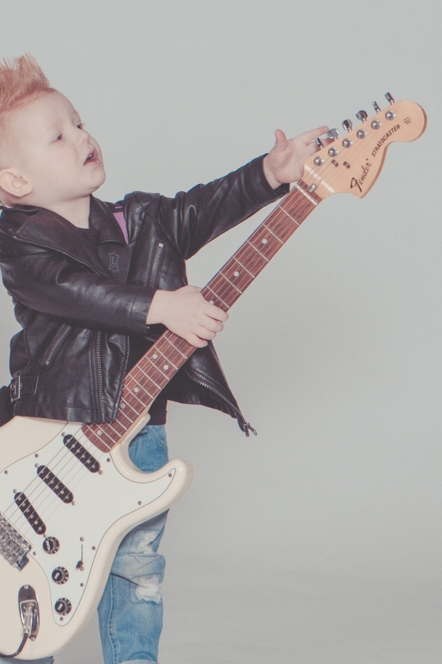 Мальчик рокер с гитарой на сером фоне