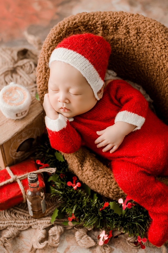 Спящий новорожденный ребенок в красном новогоднем костюме