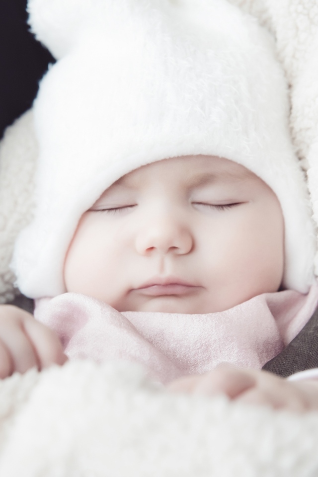 Спящий новорожденный ребенок в белой шапке