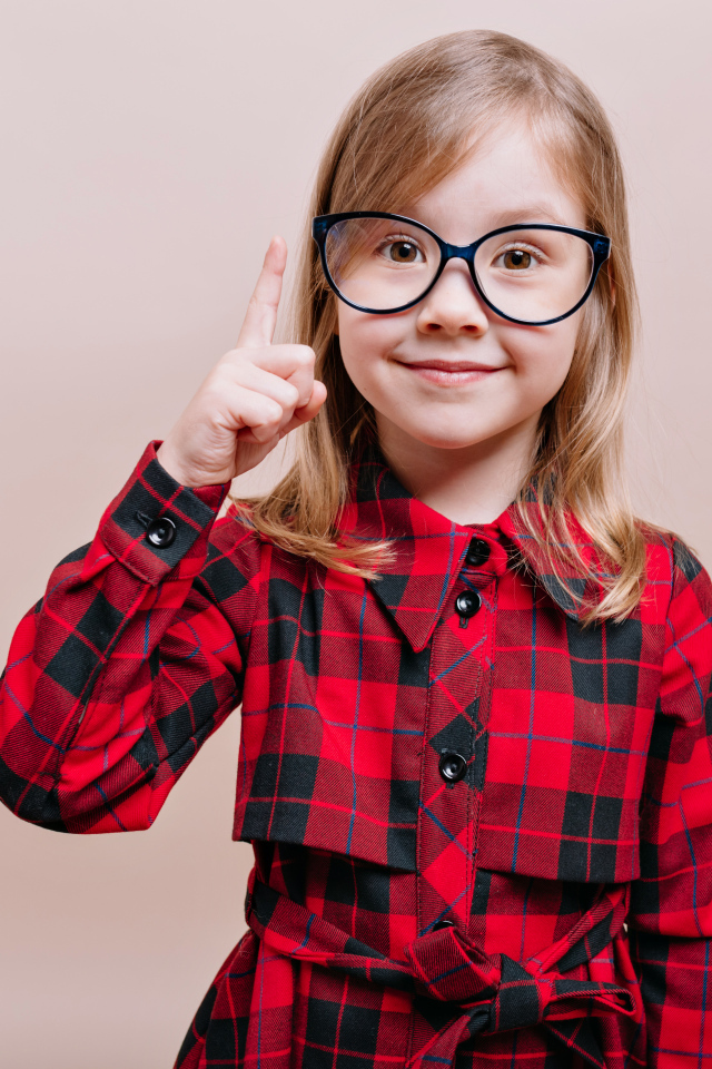 Умная маленькая девочка в платье в очках