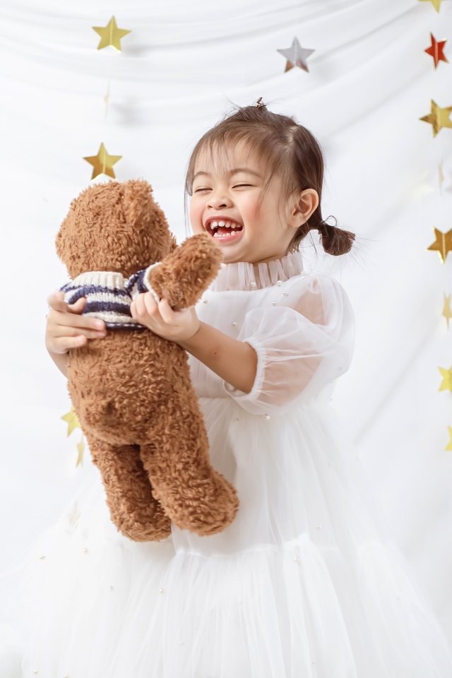 Улыбающаяся девочка азиатка с игрушечным медведем