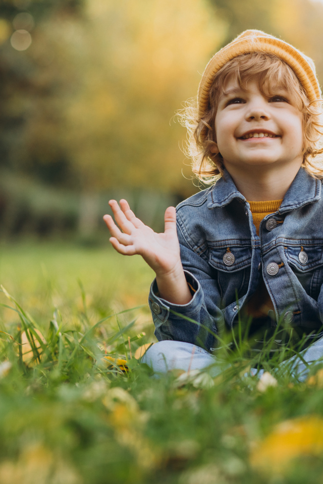 Улыбающийся ребенок сидит на траве