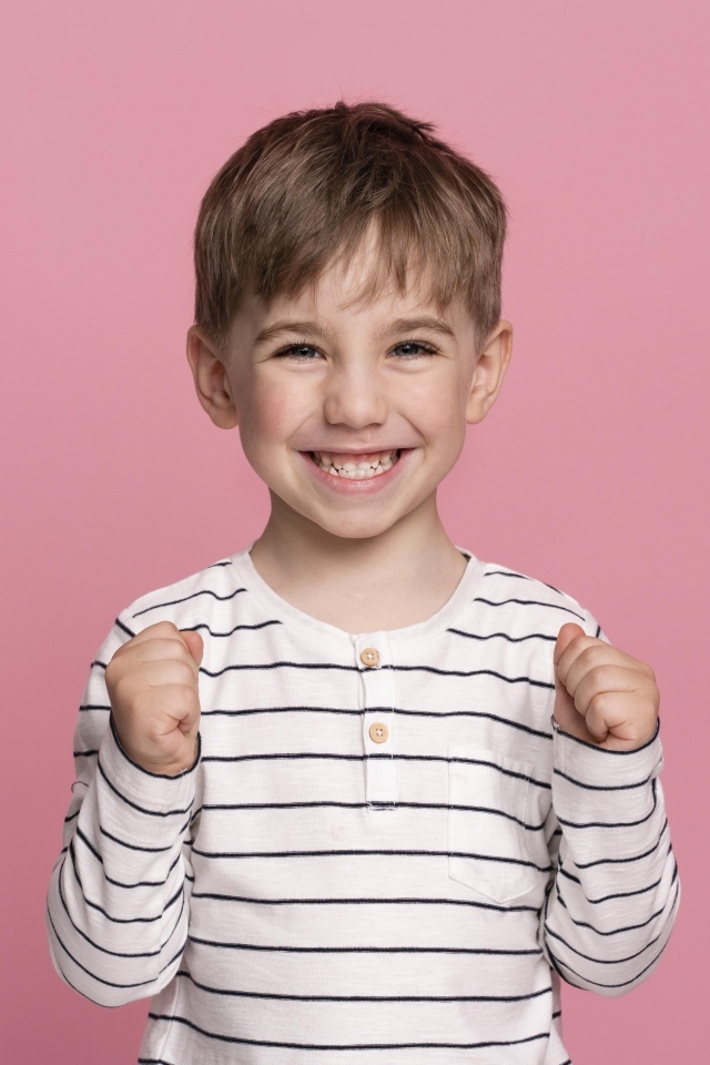 Улыбающийся маленький мальчик на сиреневом фоне