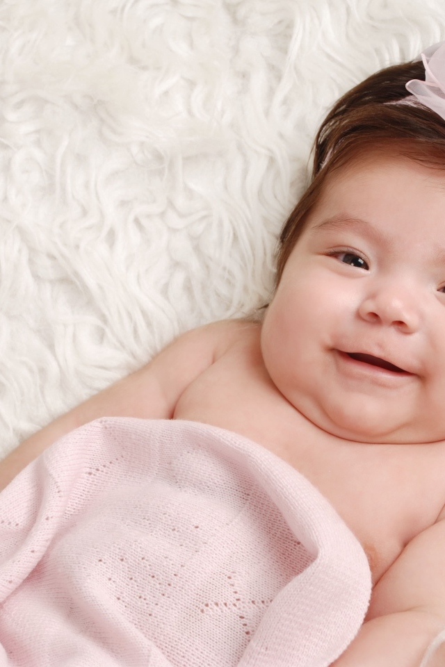Улыбающаяся новорожденная малышка с бантом на голове