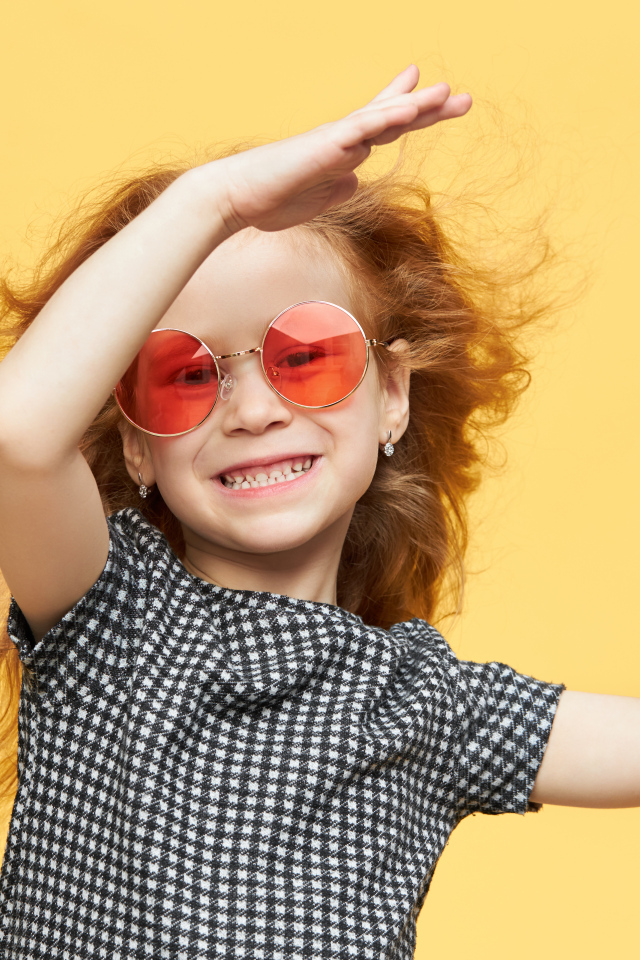 Улыбающаяся рыжеволосая девочка в очках