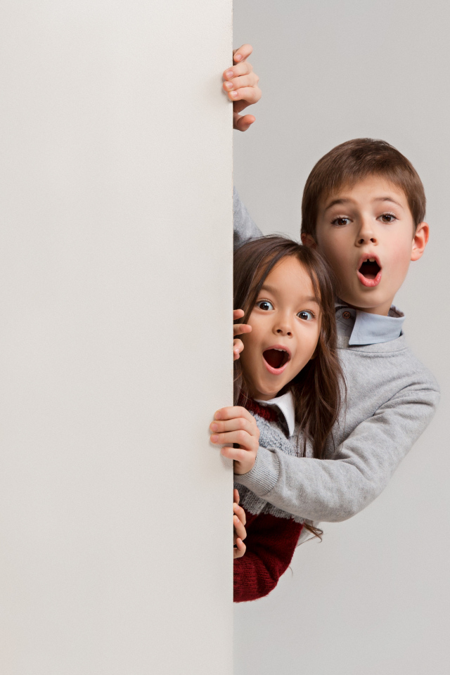 Удивленные дети выглядывают из-за угла