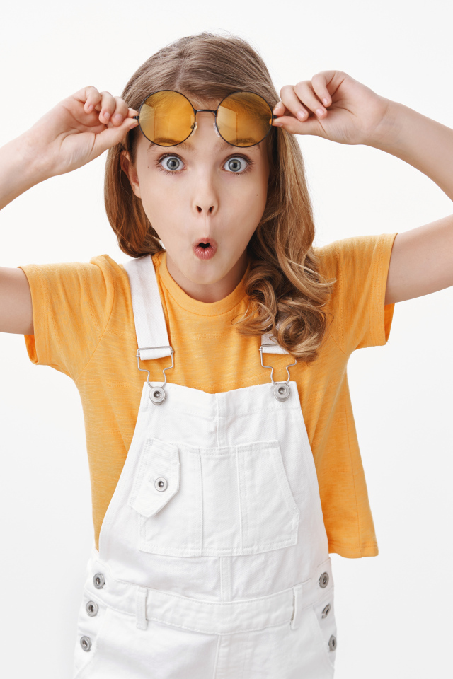 Удивленная девочка в очках на белом фоне